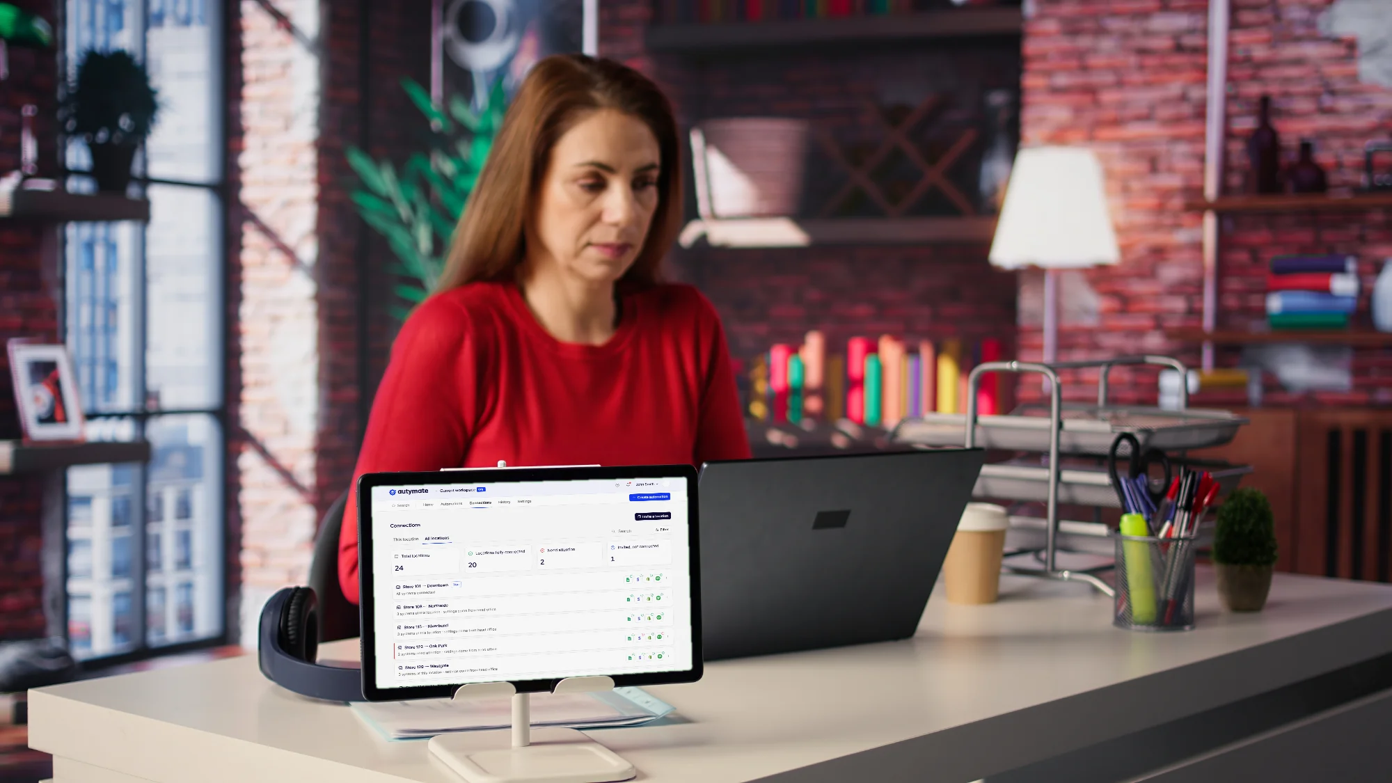 A business owner at her desk; a tablet on a stand shows the Autymate connections roster for 24 locations, each with its QuickBooks connection.