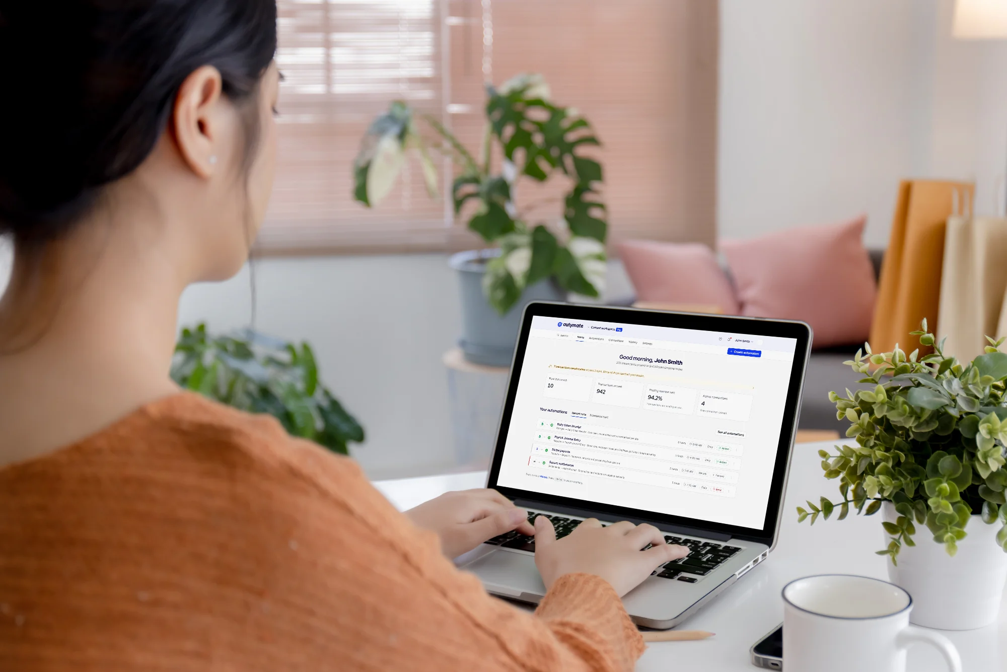 A finance worker at a home desk; the laptop shows the Autymate dashboard, with the day's transactions posted to QuickBooks Desktop.