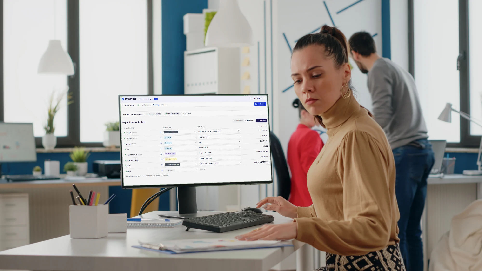 An accountant at a desktop workstation in a bright office; the monitor shows the Autymate mapping screen for a Daily Sales Receipt.